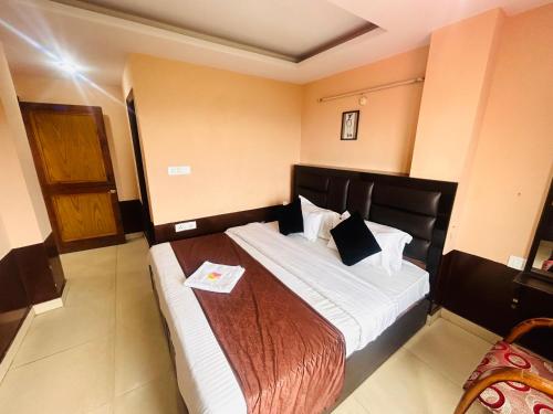 a bedroom with a large bed with a wooden headboard at HANU VATIKA The FAMILY CHOICE in Shimla