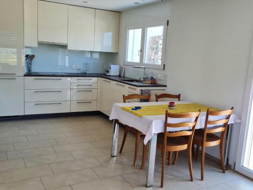 cocina con mesa con sillas y armarios blancos en Apartment Luxenweid by Interhome en Reichenburg