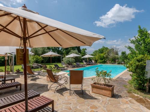 a swimming pool with chairs and an umbrella and a pool at Holiday Home Olinto by Interhome in Cinigiano