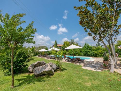 a pool with benches and umbrellas in a yard at Holiday Home Olinto by Interhome in Cinigiano
