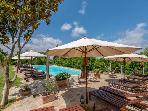 a group of chairs and umbrellas next to a swimming pool at Holiday Home Carola by Interhome in Cinigiano