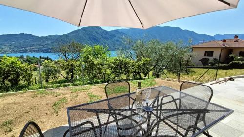 特雷梅佐的住宿－Casa del Net - Tremezzo，玻璃桌、椅子和雨伞