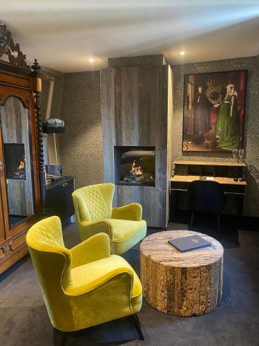 a living room with yellow chairs and a table and a fireplace at 't Hartje van Brugge in Bruges