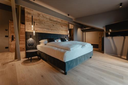 a bedroom with a large bed and a wooden wall at Hotel Alpenrose in Carezza al Lago