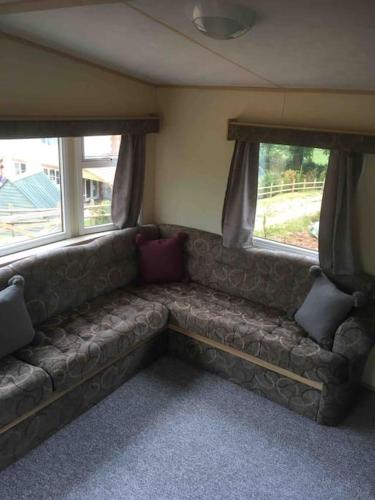 a couch sitting in a room with two windows at Park Gate, Colyton, farm,near beaches-‘Annie’ in Colyton