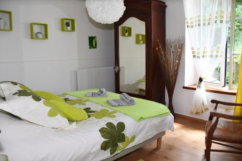 a bedroom with a bed with green blankets and a mirror at Les Volets Bleus in Provins