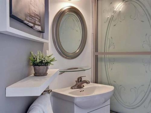 uma casa de banho com um lavatório, um espelho e um chuveiro em Bright Condo near the Lake by GLOBALSTAY em Mont-Tremblant