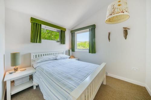 a bedroom with a bed and a table and two windows at The Billy Shed in Bridport