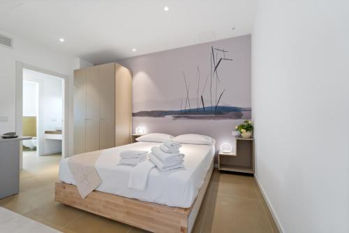 een slaapkamer met een wit bed en handdoeken bij Paquja in Quartu SantʼElena