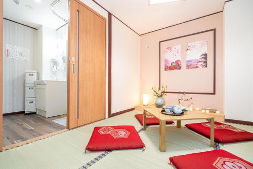 a living room with a table and red mats at NEW OPEN! Nearest JR Shinokubo and JR soubu line HIgashinakano, shinjuku 5 minute ginza 25 minute asakusa 35 minute in Tokyo