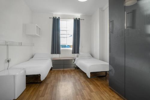 a room with two beds and a window at New Mansion House (Lancaster Gate) in London