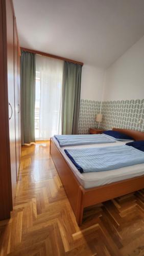 - une chambre avec un grand lit et du parquet dans l'établissement Villa Darinka, à Fažana