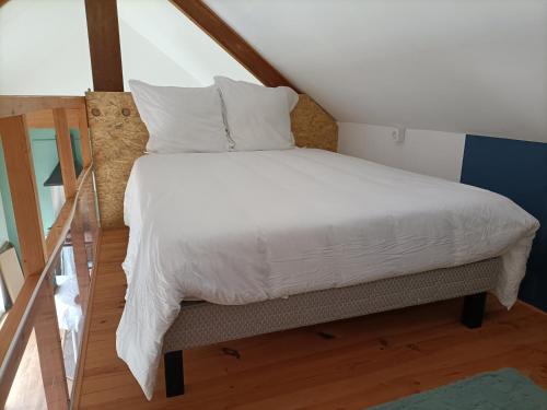 een bed met witte lakens en kussens in een kamer bij La mezzanine in Pont-Aven