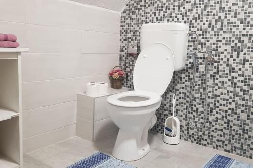 ein Badezimmer mit einer weißen Toilette in einer gefliesten Wand in der Unterkunft Orange House in Trnovo