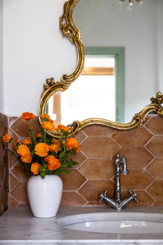 a vase of flowers on a bathroom sink with a mirror at Villa De Cillis Carafa in Torre del Greco