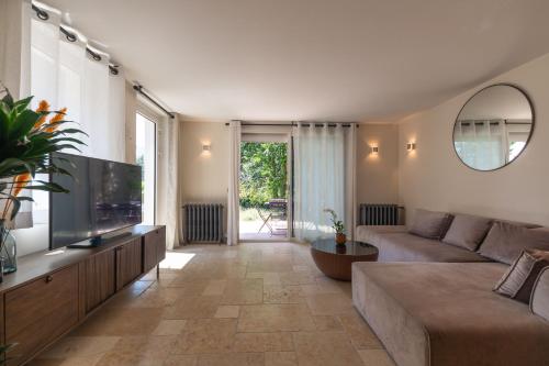 a living room with a couch and a flat screen tv at Hôtel L'Incomparable Aix-Les-Bains in Tresserves