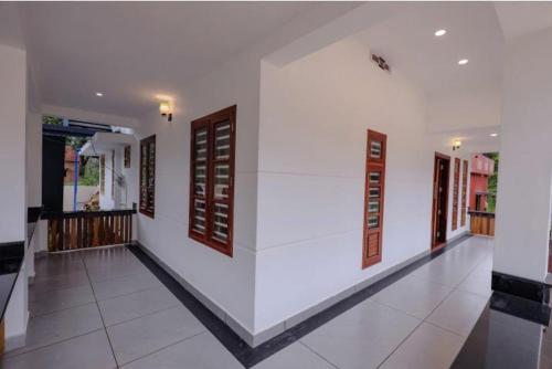 a hallway of a house with white walls and windows at Greenfield Homestay in Vythiri