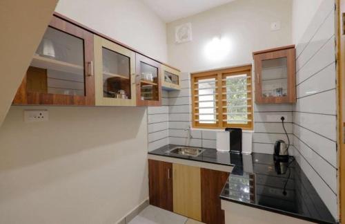 uma cozinha com armários de madeira e um balcão preto em Greenfield Homestay em Vythiri