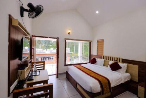 een slaapkamer met een bed, een bureau en een televisie bij Greenfield Homestay in Vythiri