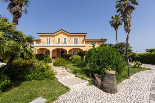een groot geel huis met palmbomen ervoor bij Villa Frida - Piscina privata ed Eventi a Lecce in San Pietro in Lama
