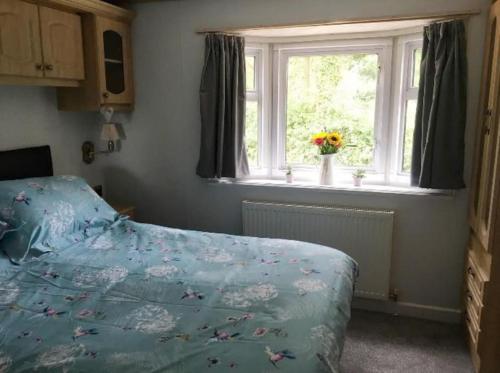 a bedroom with a bed and a window with flowers at Park gate house farm holidays, Colyton-‘Elizabeth in Colyton
