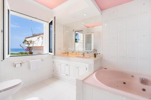 uma casa de banho com uma banheira, um WC e uma janela. em Casa Blanca by La Villa Company em Son Bou