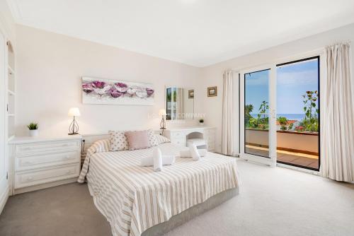 um quarto branco com uma cama e uma grande janela em Casa Blanca by La Villa Company em Son Bou