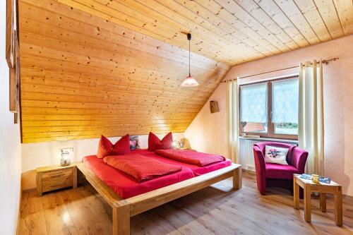 Cette chambre en bois comprend un lit rouge. dans l'établissement Furtwengler, à Oberharmersbach
