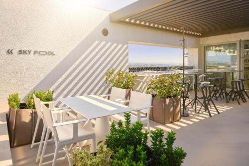 a patio with a white table and chairs and plants at Zonar Zagreb by Maistra City Vibes in Zagreb