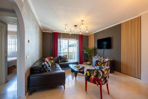 ein Wohnzimmer mit einem schwarzen Ledersofa und Stühlen in der Unterkunft Maravilloso Apartamento en Mijas Golf in Mijas
