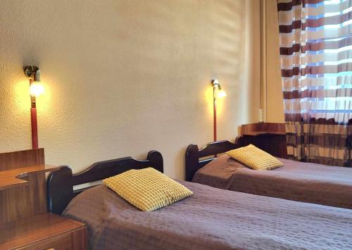 una camera d'albergo con due letti e due lampade di Ierullē a Alūksne