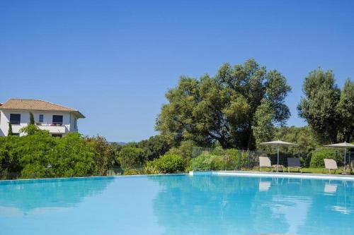 a large blue swimming pool with chairs and umbrellas at Domaine d'Arca Flaubert 20 T2 4 pers in Porto-Vecchio