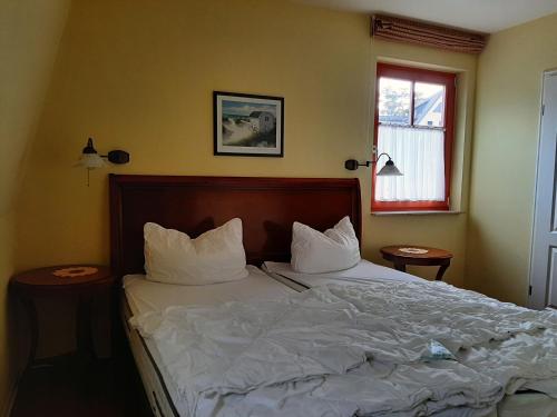 una camera da letto con letto, lenzuola e cuscini bianchi di Residenz Lausitz a Graal-Müritz