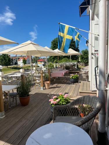 a wooden deck with tables and chairs and a flag at Göta Hotell in Borensberg