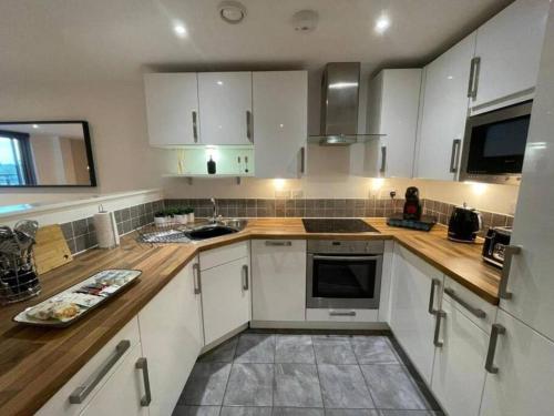 a kitchen with white cabinets and a wooden counter top at Paramount city living 105 in Swindon