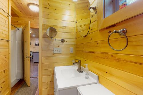 ein Badezimmer mit einem weißen Waschbecken und Holzwänden in der Unterkunft Peach Creek Lodge in Kiker