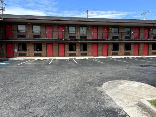 a parking lot in front of a building with red doors at Budget Plaza Motel in Brooklyn Park