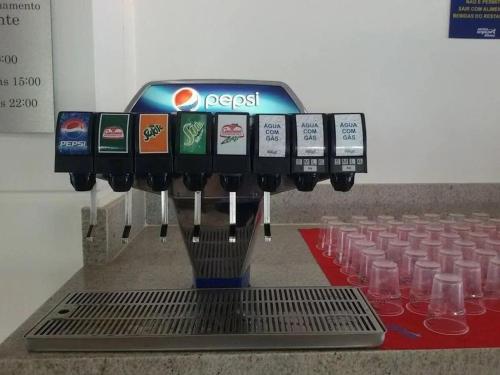 a drink vending machine with glasses on a table at Ap Completo Parq. Aquát. Sensacional Grátis in Caldas Novas