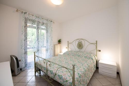 a white bedroom with a bed and a window at Orchidea Apartment in Soiano del Lago