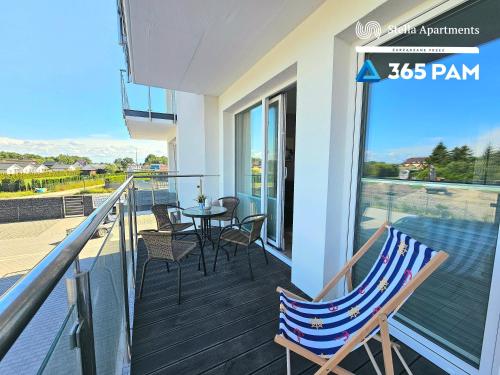 a deck with a table and chairs on a balcony at Nadmorskie Apartamenty - 365PAM in Gąski