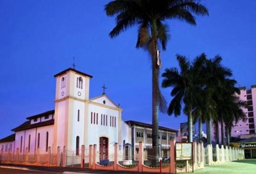 a white building with a clock tower and palm trees at Ap Completo Parq. Aquát. Sensacional Grátis in Caldas Novas