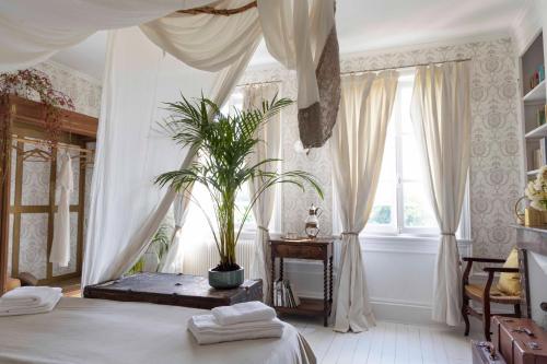 Un dormitorio con una cama con una planta. en Chambre d’hôtes au Château Le Bas Bleu, Anaïs Nin, en Quesnoy-le-Montant