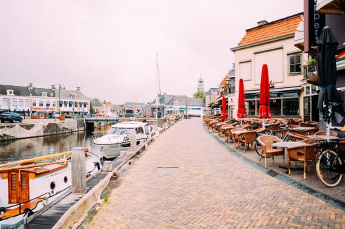 a street with tables and chairs next to a marina at Huis aan de Haven in Lemmer