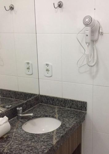 a bathroom with a sink and a phone on the wall at Ap Completo Parq. Aquát. Sensacional Grátis in Caldas Novas