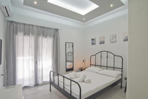 a white bedroom with a bed and a window at Sofias Home in Piraeus