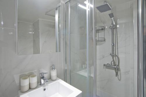 a white bathroom with a shower and a sink at Sofias Home in Piraeus