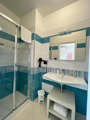 a blue and white bathroom with a sink and a shower at Milena Suite Apartments in Alghero