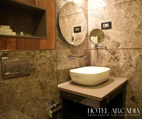 y baño con lavabo y espejo. en Hotel Arcadia, en Kottayam
