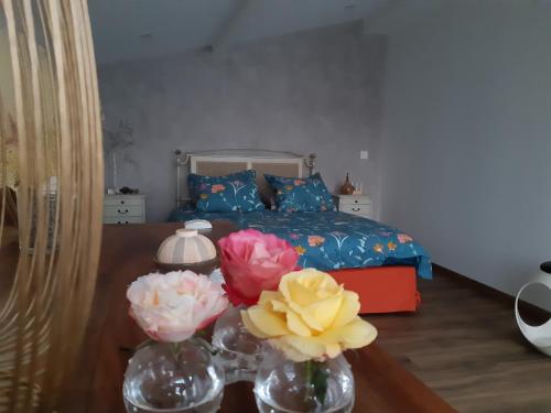 a bedroom with a bed and flowers in vases on a table at Un petit coin de paradis à Haute Jarrie in Jarrie