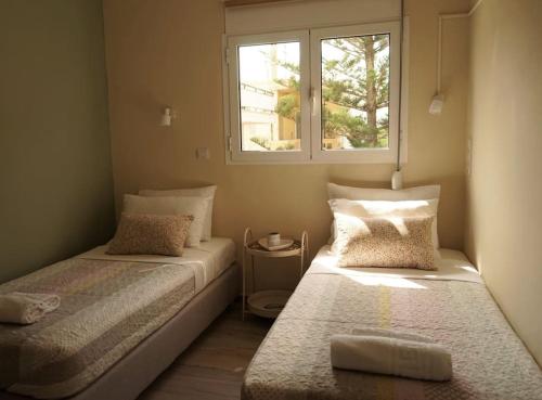 two beds in a small room with a window at Frezia House in Kalamaki Chanion